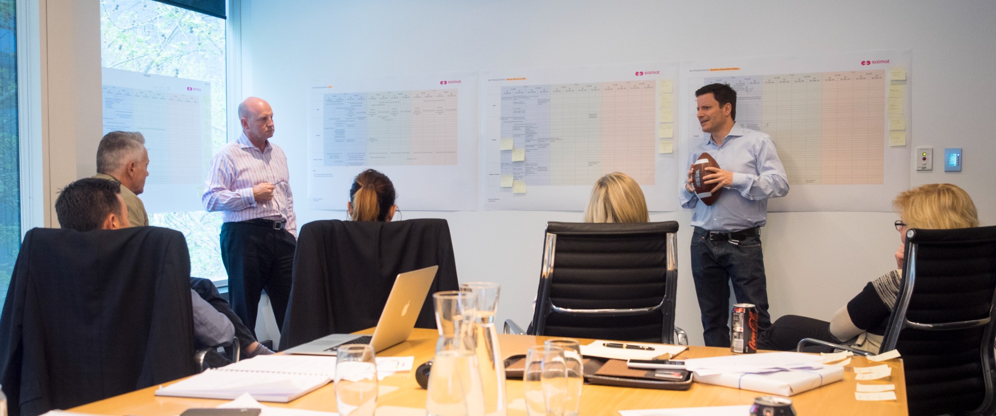 James Alvetro working shoulder-to-shoulder with a leadership team around a visible wall of priorities